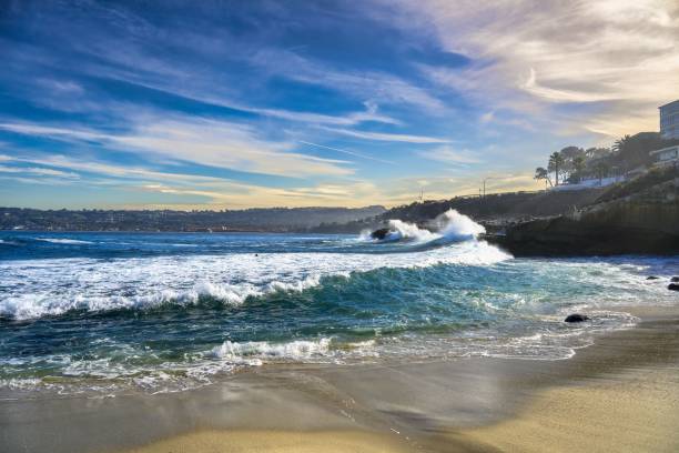 Waves Crashing at La Jolla Cove with Water Spray and Blue Sky Waves crash against the rocks at La Jolla Cove, with water spraying and a light blue sky in California. la-jolla stock pictures, royalty-free photos & images