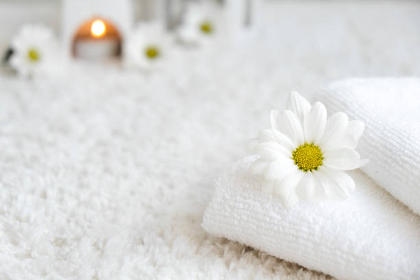 White towels with chamomile flower and aroma lamp, candle. Spa and wellness or beauty salon, romantic relaxation concept. Copy space. Womens Day. Valentines Day.