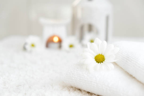 White towels with chamomile and aroma lamp, candle on background. Spa resort therapy and wellness, aromatherapy relaxation. Body care and treatment. Self Love. Copy space.