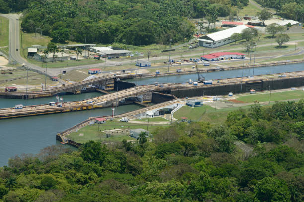 An aerial view of the Panama Canal lock system, showcasing the intricate engineering used to control water levels and facilitate ship navigation. Surrounded by lush greenery, this iconic structure is a cornerstone of global trade.