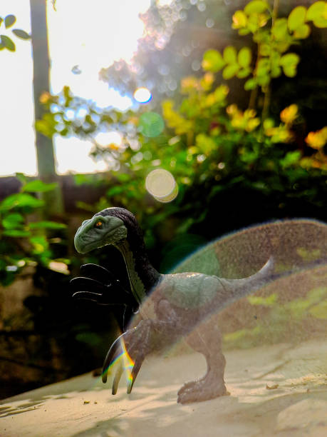istock A macro shot showcasing a dinosaur toy with a lifelike appearance, perched on a wooden surface with a backdrop of vibrant greenery. The image evokes a sense of prehistoric wonder 2191793247