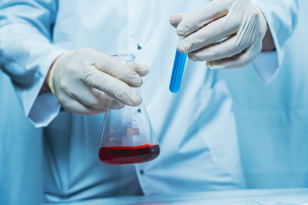 istock Scientist handling flask with red liquid and blue test tube 2191793784