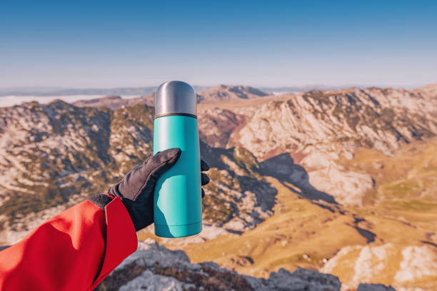 istock Climber showing a thermos bottle with a mountain peak scenery with valley below in the background 2191795021