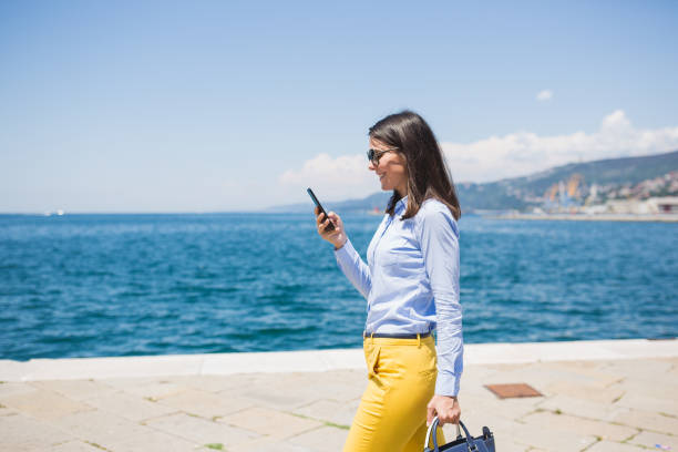 istock Young Woman Using Smartphone by the Sea During Daytime 2191799718