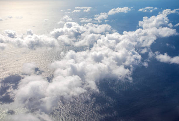 Beautiful, dramatic a group of clouds in the sky over the ocean viewed from a height from inside an airplane.