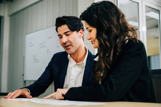 istock Colleagues in an office setting, working together and planning their business strategy. Teamwork is key as they discuss documents, analyze graphs, and aim for success. 2191808735