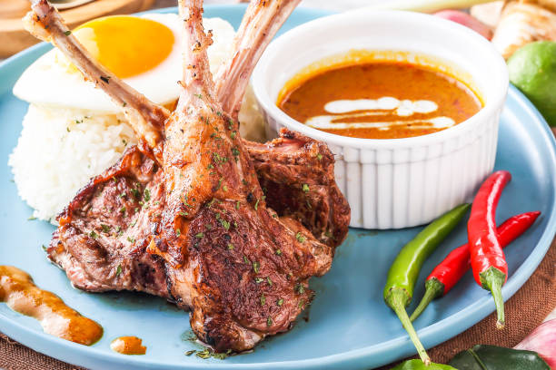 Pan fried Lamb Rack or lamb chops with with curry, rice and sunny side up egg served in plate with chili peppers isolated on napkin closeup side view of hong kong food
