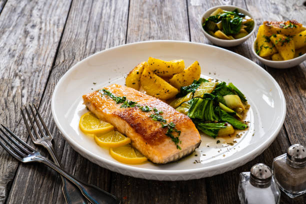 istock Fried salmon, fried potatatoes with stir-fried bok choy on wooden table 2191817203