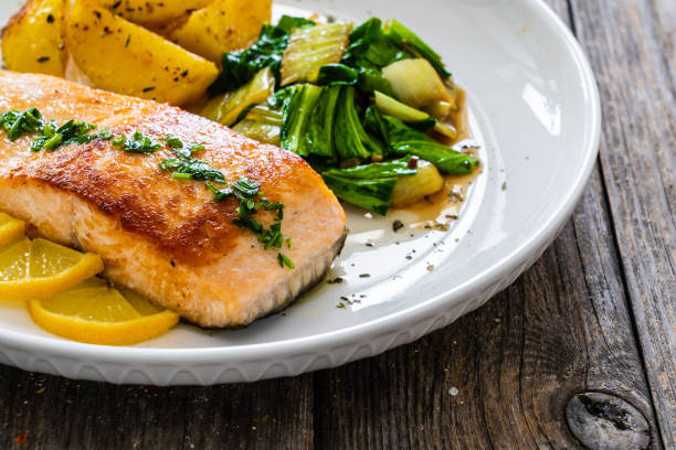 istock Fried salmon, fried potatatoes with stir-fried bok choy on wooden table 2191817218