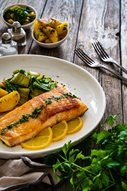 istock Fried salmon, fried potatatoes with stir-fried bok choy on wooden table 2191817228