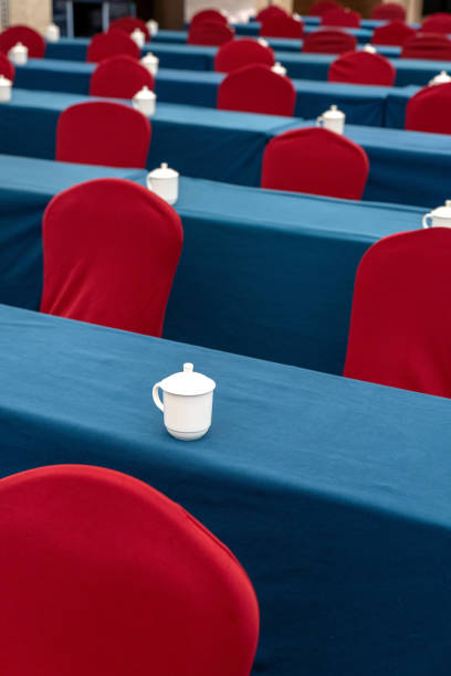Rows of red chairs, white cups on blue tables