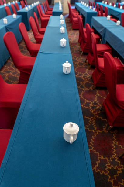 Rows of red chairs, white cups on blue tables