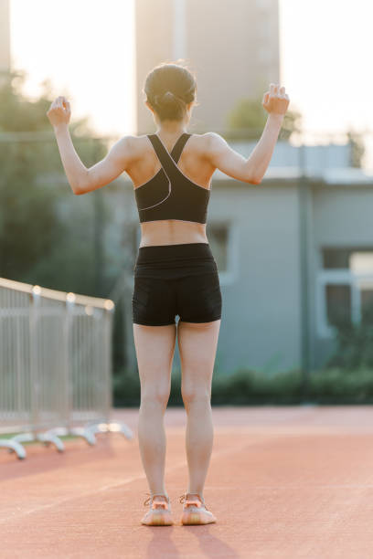 istock The athlete performs a stretch, her hands clasped behind her head, on the outdoor track 2191821622