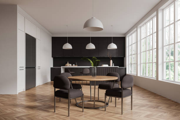 istock Modern kitchen dining area with black cabinets, wooden table, and large windows in a bright room. 3D Rendering 2191822915