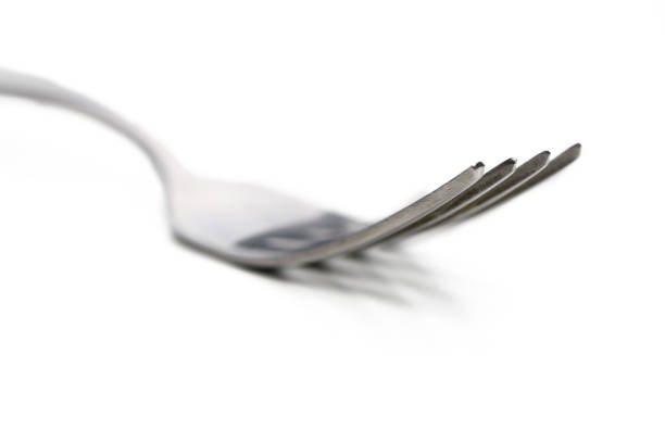 Silver fork detail on light shaded background. Focus on foreground