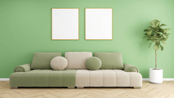 istock A cozy and inviting living room with a calming green wall, a comfortable sofa with cushions, two empty frames, a floor lamp, and a potted plant. 2191825838