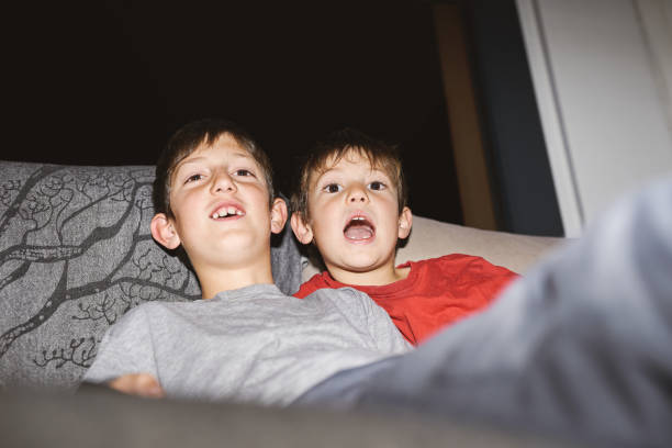istock Two boys sitting on a couch, laughing and expressing excitement indoors. 2191827382
