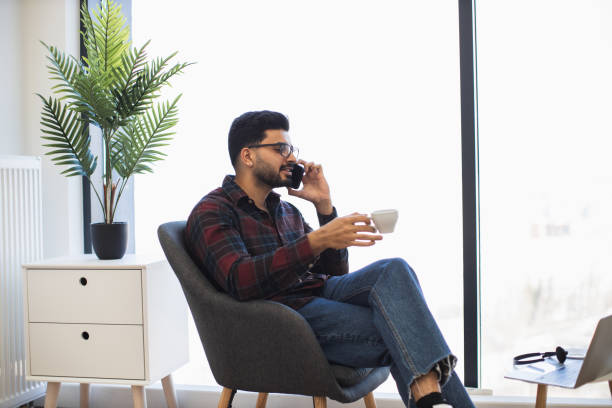 istock Indian man enjoying coffee while talking on phone at home 2191828151