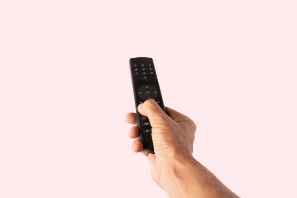 istock Male hand holding a tv remote controller isolated on pink background cutout 2191828484