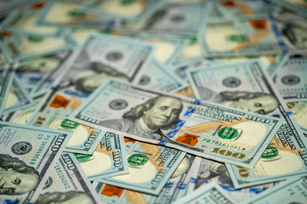 istock Variety of hundred dollar bills scattered on a flat surface 2191831936