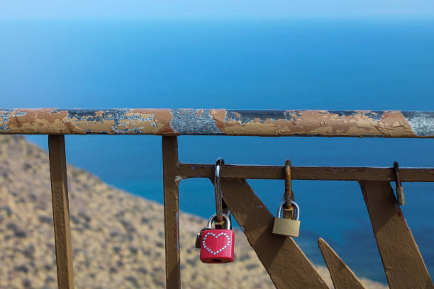 Padlock with a heart on a fence or railing on a rock above the sea. Romantic gesture