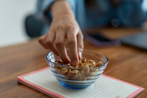 istock Hand picking walnuts from a glass bowl on a notebook - energy and focus during remote work 2191836420