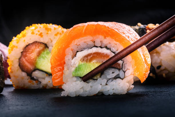 istock Sushi rolls on a black background. Uramaki with salmon and avocado 2191842343