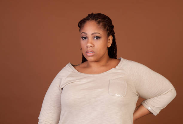 Beautiful plus size black woman standing on a brown background