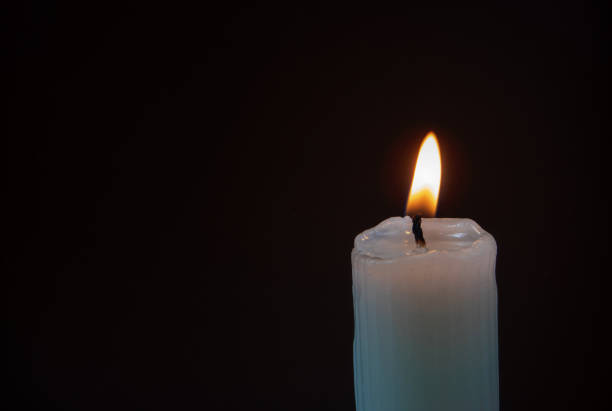 istock Burning ribbed pillar wax candle on the dark background 2191844386