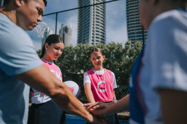 Australian young netball team players huddling stacking hands before the game start with coach