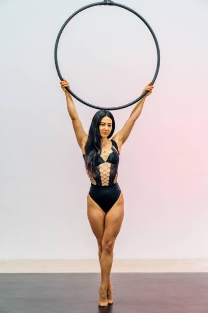 Female portrait of woman who working in circus as performer and acrobatic artist. Girl wear beautiful dress indoors. Photo with circus hoop