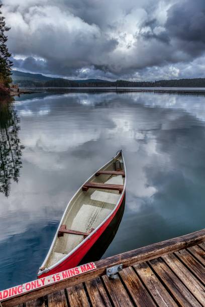 istock Serene lake with red canoe and dramatic clouds 2191852478