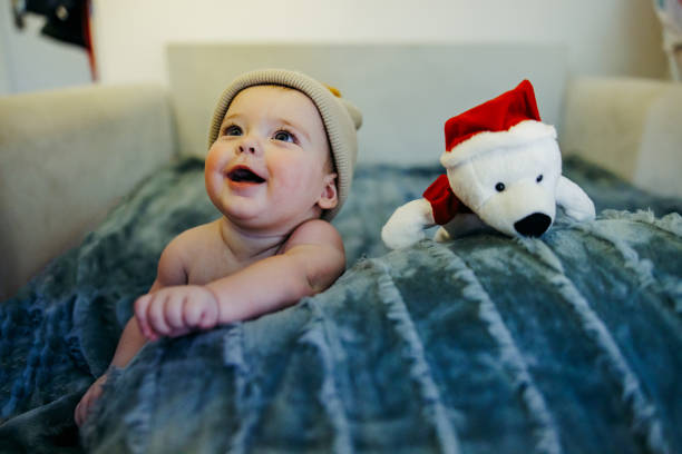 Smiling baby with teddy bear in the bed