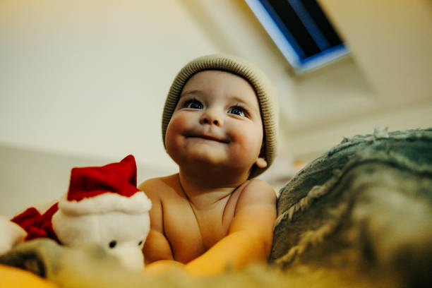 Happy baby with stuffed toy lying in the bed