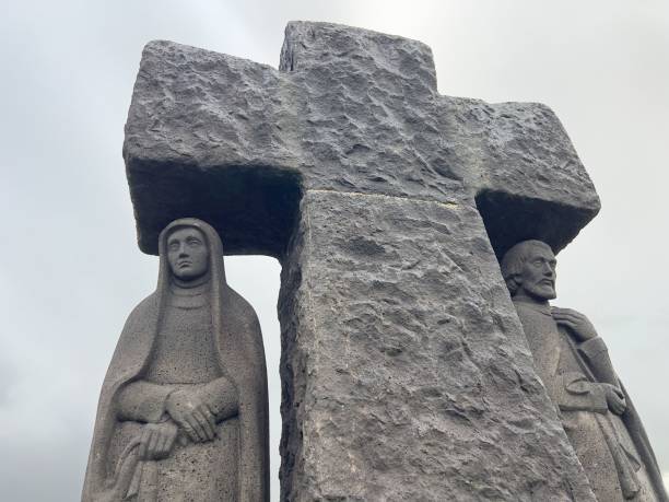 istock Stone statues with a large cross under cloudy sky. 2191853909
