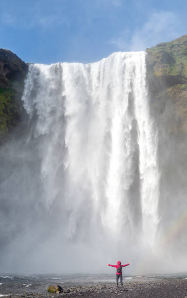 istock Skogafoss waterfall with an unidentified woman under the waterfall and a rainbow, Skogar, Iceland 2191865576