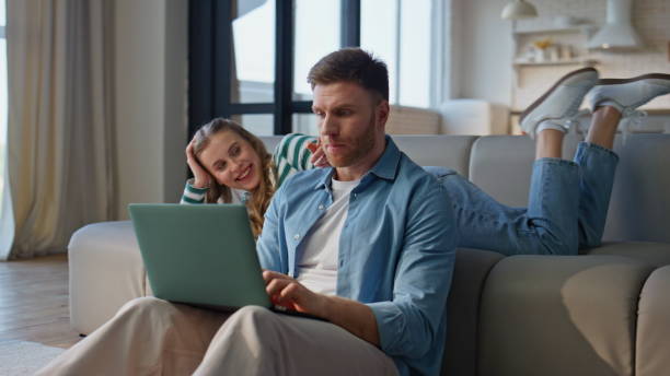 istock Serious man working laptop bored girlfriend leaning at sofa distracted husband 2191866183