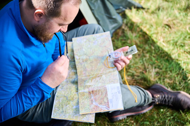 istock Close up man in glasses closely examines map while holding compass. 2191868179