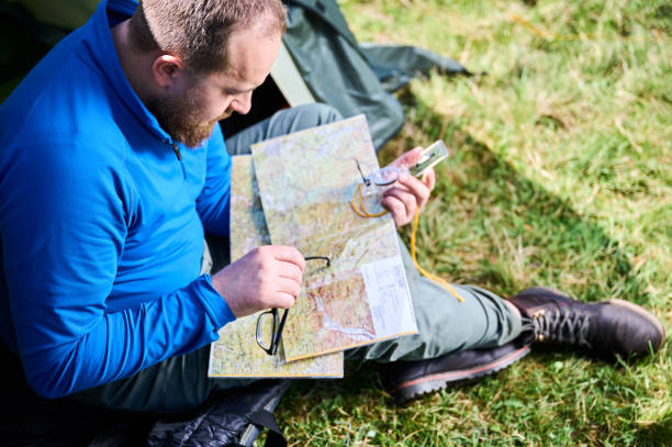 istock Close up man in glasses closely examines map while holding compass. 2191868187