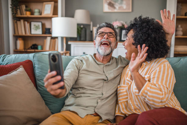 istock A middle-aged couple waves directly at the camera while making a video call from the living room 2191869767