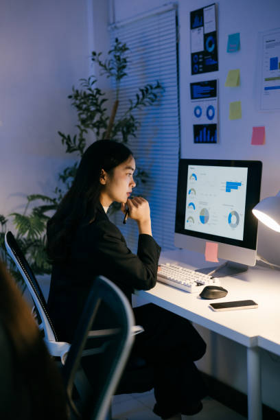 istock Young asian businesswoman concentrating on computer screen, analyzing financial data and business performance, working late in a modern office 2191871714