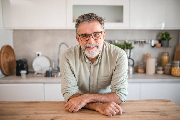 istock A smiling middle-aged man looks directly into the camera while standing at the kitchen counter 2191871794