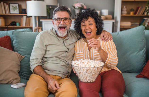istock Happy multiracial loving couple eating popcorn and watching comedy while sitting on sofa in living room 2191872599