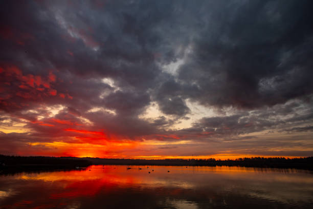 A breathtaking sunset featuring vibrant and warm colors gently reflecting on the serene water beneath moody skies