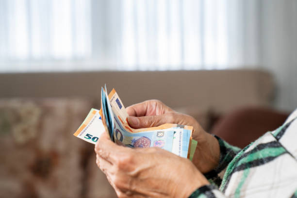 istock Close-up of elderly woman's hands holding a stack of euro banknotes 2191884142