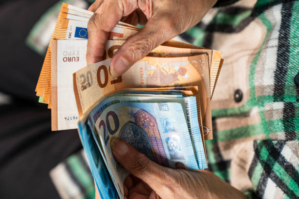 istock Close-up of elderly woman's hands holding a stack of euro banknotes 2191884178