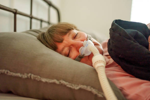 istock Woman in Her sixties with sleep apnea getting rest and sleep using a modern CPAP machine in a dark bedroom 2191888552