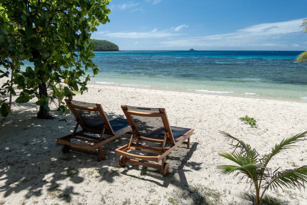 istock A tropical beach with brown deck chairs, a blue channel, and distant coral, perfect for sunbaking 2191890816