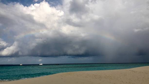 istock Rainbow in front of thick cloud in the sky, above a beach after rain 2191900715