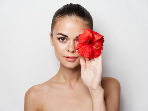 istock woman with red flower in hand bare shoulders cropped view model 2191911154